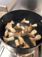 Load image into Gallery viewer, Oyster mushrooms boiling in water inside a black non-stick pot on a stovetop.
