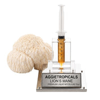A rounded Lion's Mane mushroom formed of cascading white icicle-like spines, beside a syringe filled with liquid mycelium culture mounted on a mirrored stand, labeled "AGGIETROPICALS, LION'S MANE, PREMIUM LIQUID MYCELIUM 10cc", on a white background.