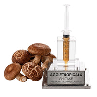 A cluster of Shiitake mushrooms with brown caps and cream-colored gills on thick stems, beside a syringe filled with liquid mycelium culture mounted on a mirrored stand, labeled "AGGIETROPICALS, SHIITAKE, PREMIUM LIQUID MYCELIUM 10cc", on a white background.
