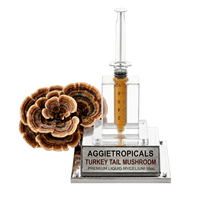 A clear acrylic and glass turkey tail mushroom mycelium kit by Aggietropicals, featuring a clear syringe-style container with amber liquid and a matching turkey tail mushroom specimen on a silver base.