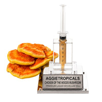 A Chicken of the Woods mushroom formed of bright orange-yellow shelf-like fan clusters, beside a syringe filled with liquid mycelium culture mounted on a mirrored stand, labeled "AGGIETROPICALS, CHICKEN OF THE WOODS, PREMIUM LIQUID MYCELIUM 10cc", on a white background.